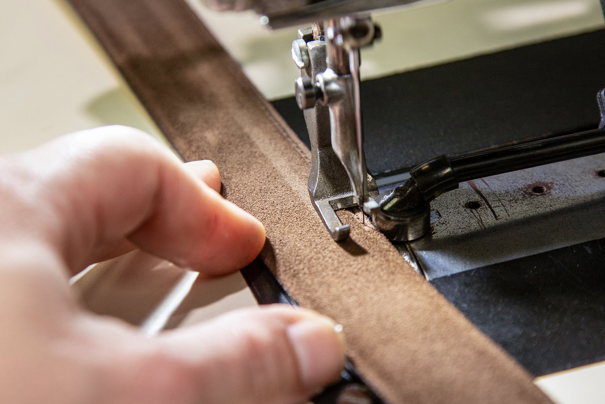Goldfels leather strap in Havana Brown is moved by hand through a sewing machine.