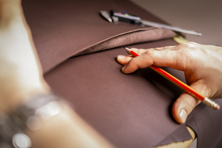 Craftsman working on a piece of chocolate calfskin leather from Goldfels.